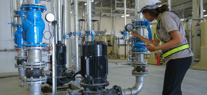 Technician checking pressure gauges on industrial compressed air equipment during an inspection